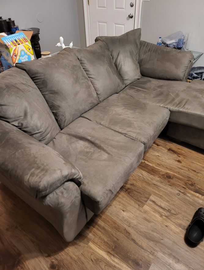 A worn, sagging mass-produced sectional in a living room